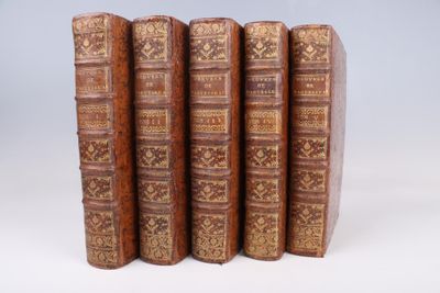 six vieux livres sont alignés sur une surface blanche