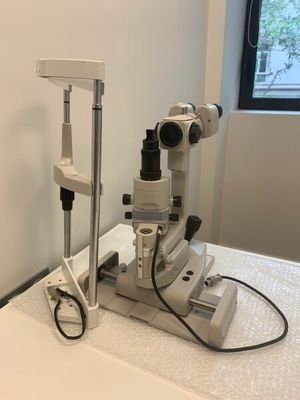 une table blanche sur laquelle est posé un microscope, dans une pièce