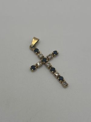 une croix en or ornée de pierres bleues et blanches sur un fond blanc