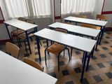 tables and chairs in an empty classroom with a checkered floor