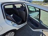 a small white car with its door open on the street