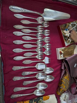 de nombreuses cuillères en argent et des cuillères à soupe posées sur une table