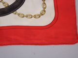 a red and white square with a black and gold chain on it