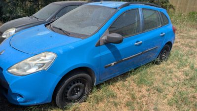 two small cars parked in the grass next to each other