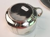 a silver tea pot sitting on a table next to a plate