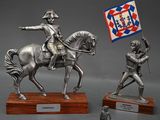 silver statue of a man on a horse holding a flag and a man on a horse holding a flag