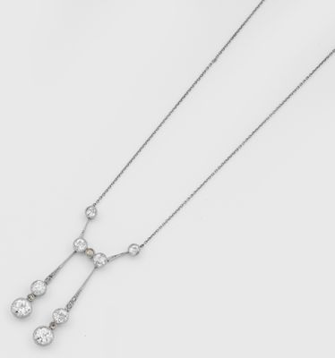 un gros plan d'un collier en diamants posé sur une surface blanche