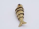 an image of a gold fish charm with a purple stone on it