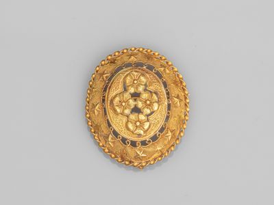 gros plan d'une broche en or sur une surface blanche