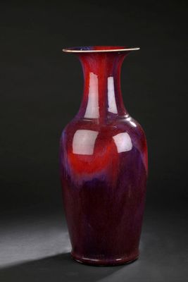 a red vase sitting on a black surface