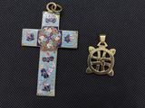 a cross and a small pendant are sitting next to each other