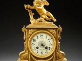 a gold clock with an angel on top of it