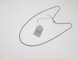 a silver necklace with a tag on it on a white surface