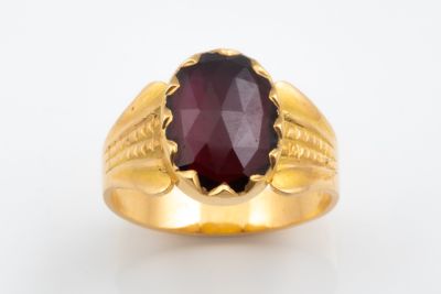 gros plan d'une bague en or avec une pierre rouge