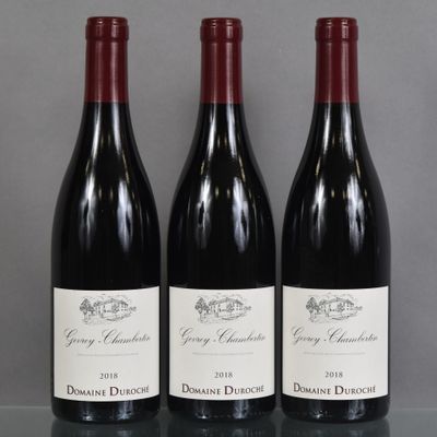 three bottles of red wine are lined up on a table