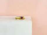 un gros plan d'une bague en or ornée d'une pierre rouge