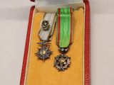 two medals in a red case on a white table