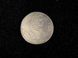 an old silver coin with a crown on it on a black surface