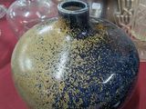 un vase bleu et jaune posé sur une table rouge