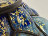 a close up of a blue vase with gold paint on it