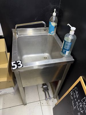 a stainless steel sink in the corner of a bathroom