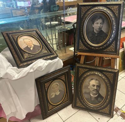 trois portraits encadrés d'hommes et de femmes sont posés sur une table devant une vitrine