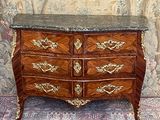 a marble top chest of drawers in front of a floral wallpaper