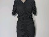 La robe est noire et présente un motif froncé.