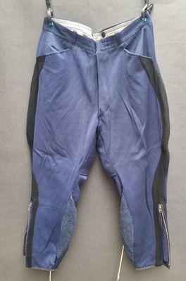 blue pants with zippers hanging on a hanger on a wall