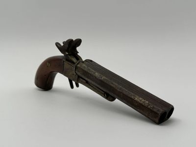 un vieux pistolet jouet avec une crosse en bois posé sur une surface blanche