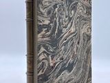 an old book sitting on top of a white table next to a white wall