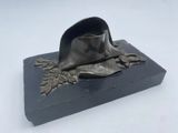 statue représentant un chapeau posé sur un socle orné de feuilles