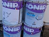 trois seaux de peinture posés par terre près d'un mur