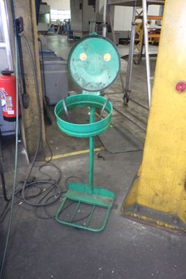 une poubelle verte posée sur un support dans un garage