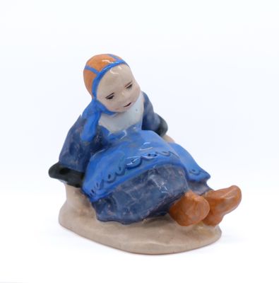 une figurine représentant une femme assise sur un rocher