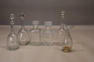 cinq bouteilles en verre et une petite bouteille en verre posées sur une table