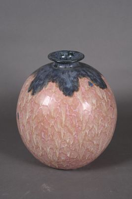 un vase rose et noir posé sur une surface grise