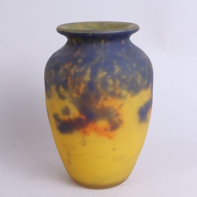 un vase jaune et bleu posé sur une surface blanche