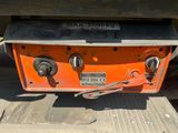 the back end of an orange truck with a metal plate on it