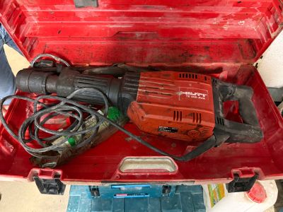 une boîte à outils rouge contenant une perceuse et un cordon d'alimentation