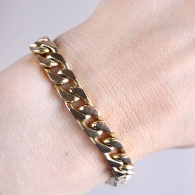 bracelet plaqué or au poignet d'une femme, entouré d'une chaîne