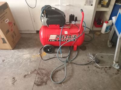 a red air compressor sitting on the floor in a garage