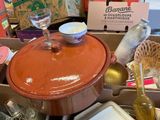 a red pot sitting on top of a table next to a wine glass