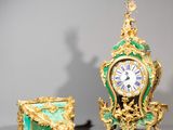 une horloge dorée et verte posée à côté d'une boîte verte