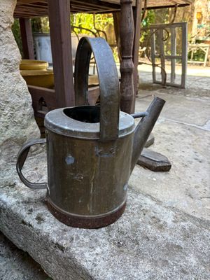 a small watering can sitting on a stone slab