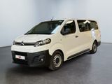 La camionnette blanche est garée dans une grande pièce au sol noir.