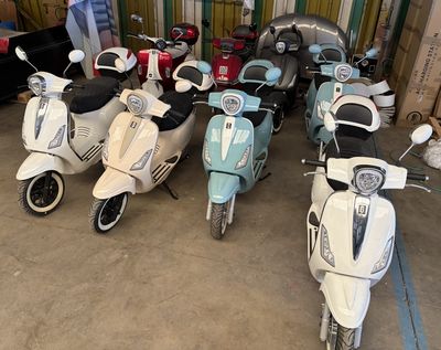 Plusieurs scooters sont alignés les uns à côté des autres dans un garage