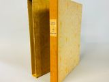 un livre ouvert, à la couverture jaune, posé sur une surface blanche