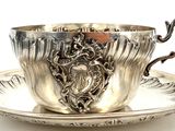 a silver tea cup and saucer on a saucer
