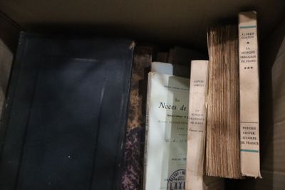 de nombreux livres anciens dans une boîte posée par terre
